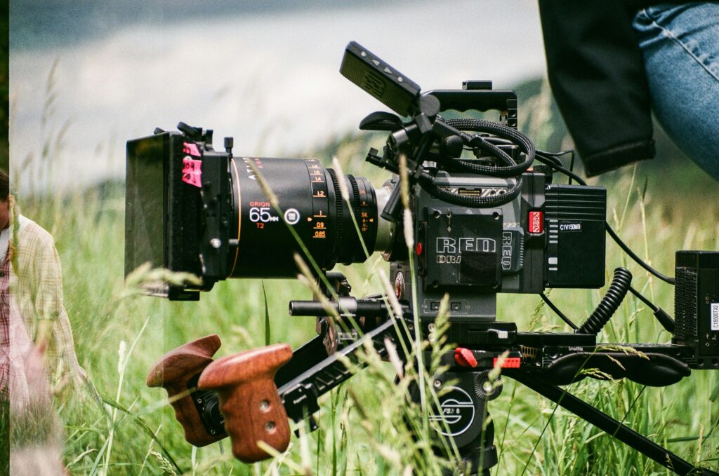 Close up of a black film camera surrounded by green grass