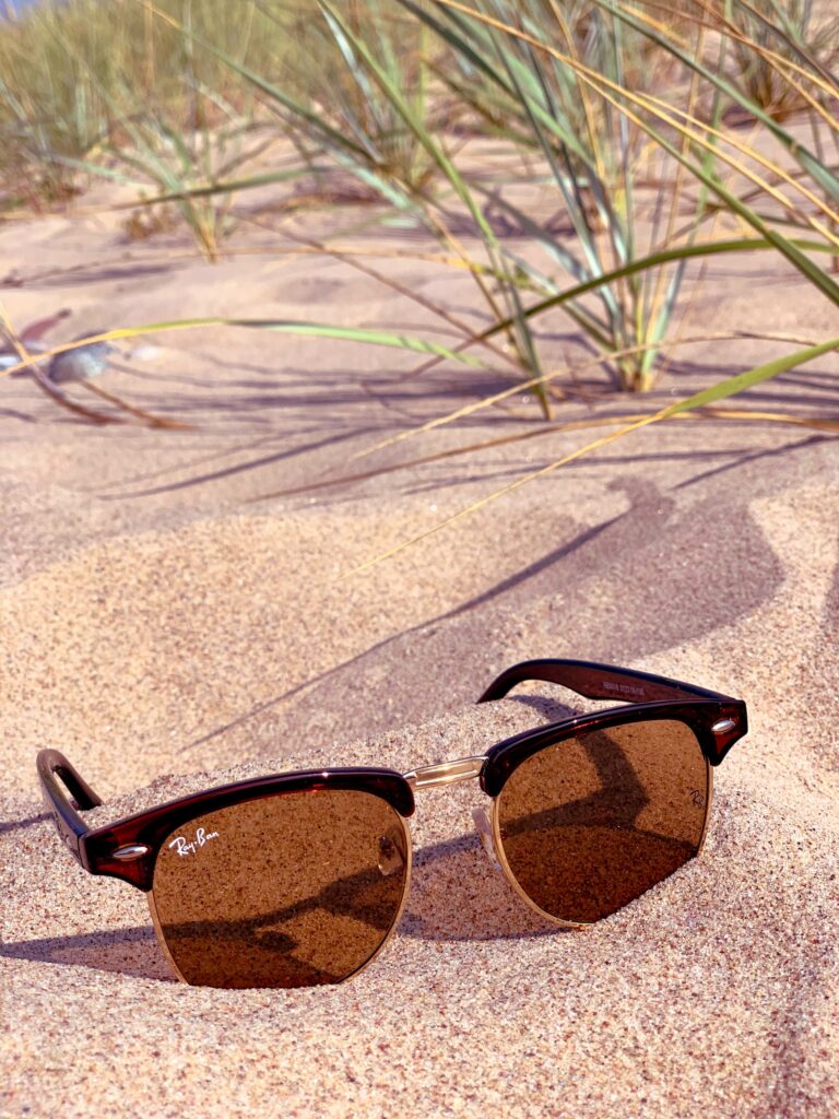 Close up image of a pari of sunglasses in some sand 