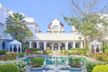 Image of Taj Lake Palace showing white marble building behind a colourful garden