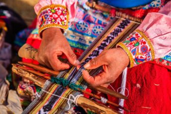 Peruvian woman demonstrating traditional weaving techniques with vibrant fabric in Peru