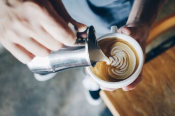 Barista pouring milk into coffee
