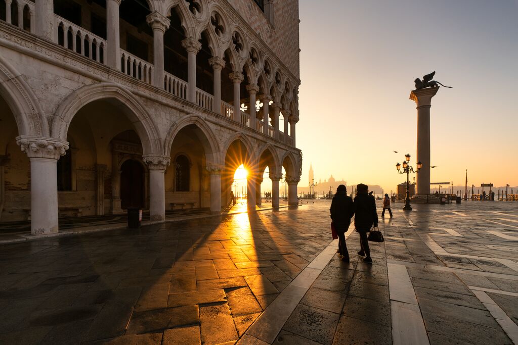 Two people walking past the Doge's Palace in St. Mark's Square, Venice