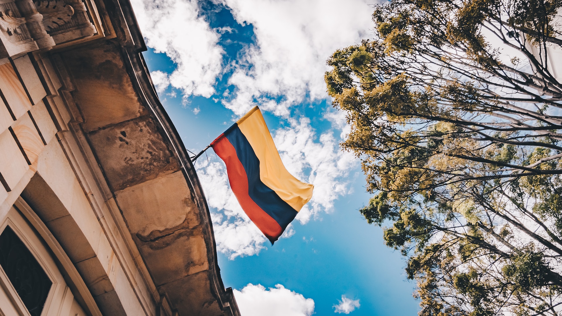 Worms eye view of Colombian flag on tip of building