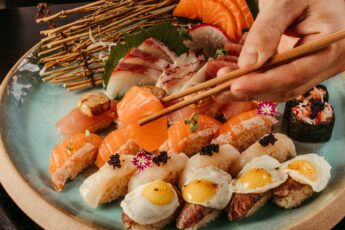 Plate of high-end sushi, with a hand holding chopsticks