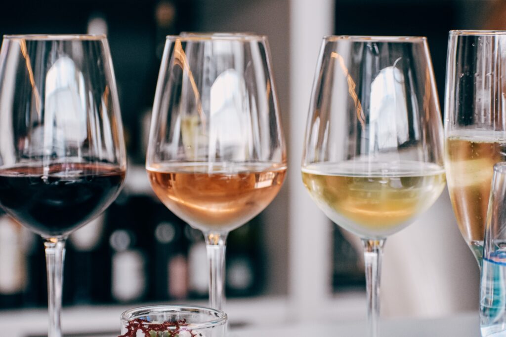 Close up of three wine glasses, presented for a tasting, one with red, one with rose and one with white in a small amount.