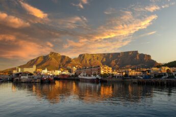 Table Mountain in South Africa at sunset, with the sea in front and a cloudy evening sky