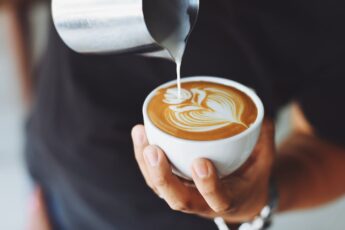 Close up of barista pouring coffee with coffee art on top