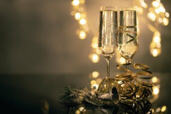 Closeup of 2 champagne flutes with lights in background