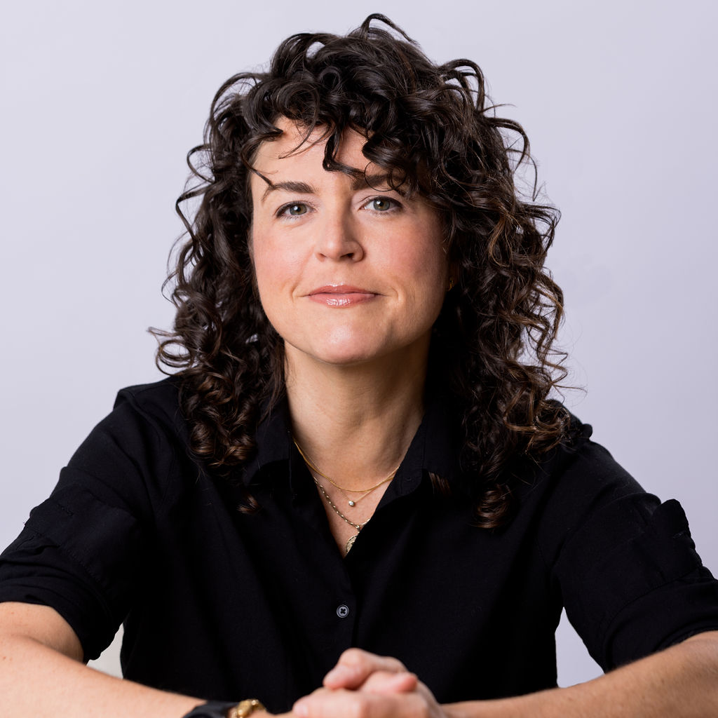 Shannon Guihan, TTC Chief Sustainability Officer faces the camera, wearing a black top with hands clasped together