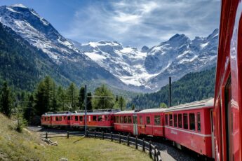 The Glacier Express - photo taken POV-style from inside the train, looking along the carriages to the front, with mountains in the distance