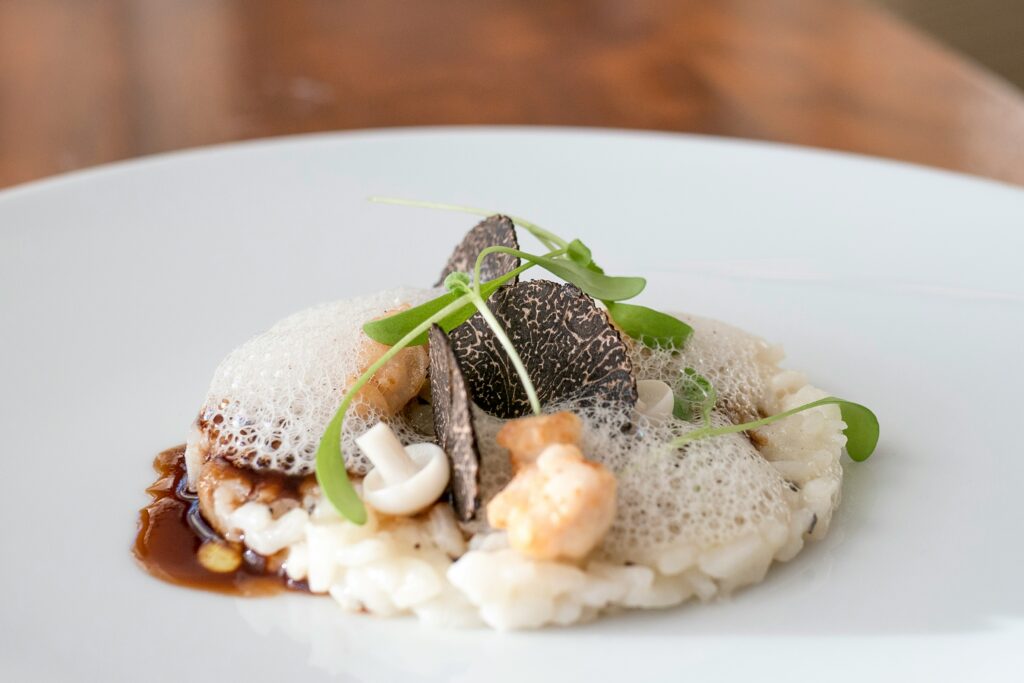 Aged Carnaroli Rice Risotto, Crispy Sweetbreads, Burgundy Truffle, Pickled Mushrooms served on a white dish.