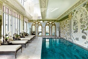 Aqua marine water sits in a long, thin indoor plunge pool at Asford castle spa, with white comfoy seats along the edge and ornate decorations on the walls.