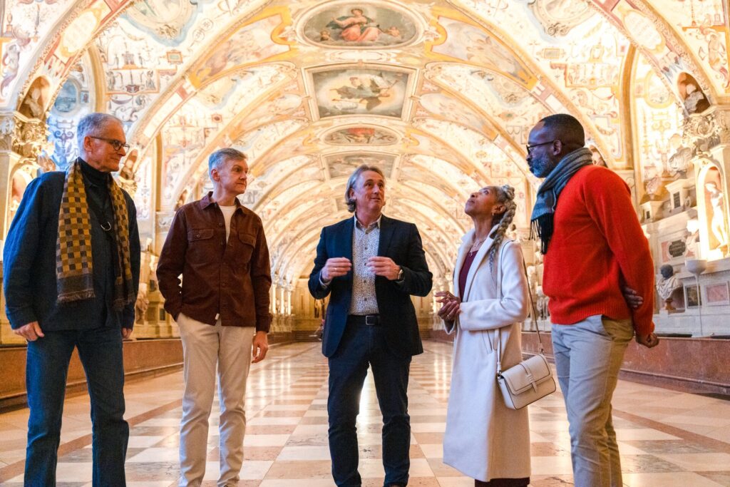 Guests stand with a Travel Director in an ornate palace.