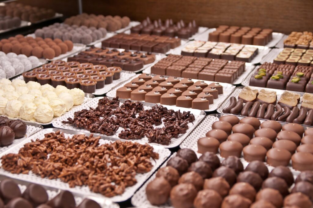 Nest rows of tiny chocolates are on display on white trays.