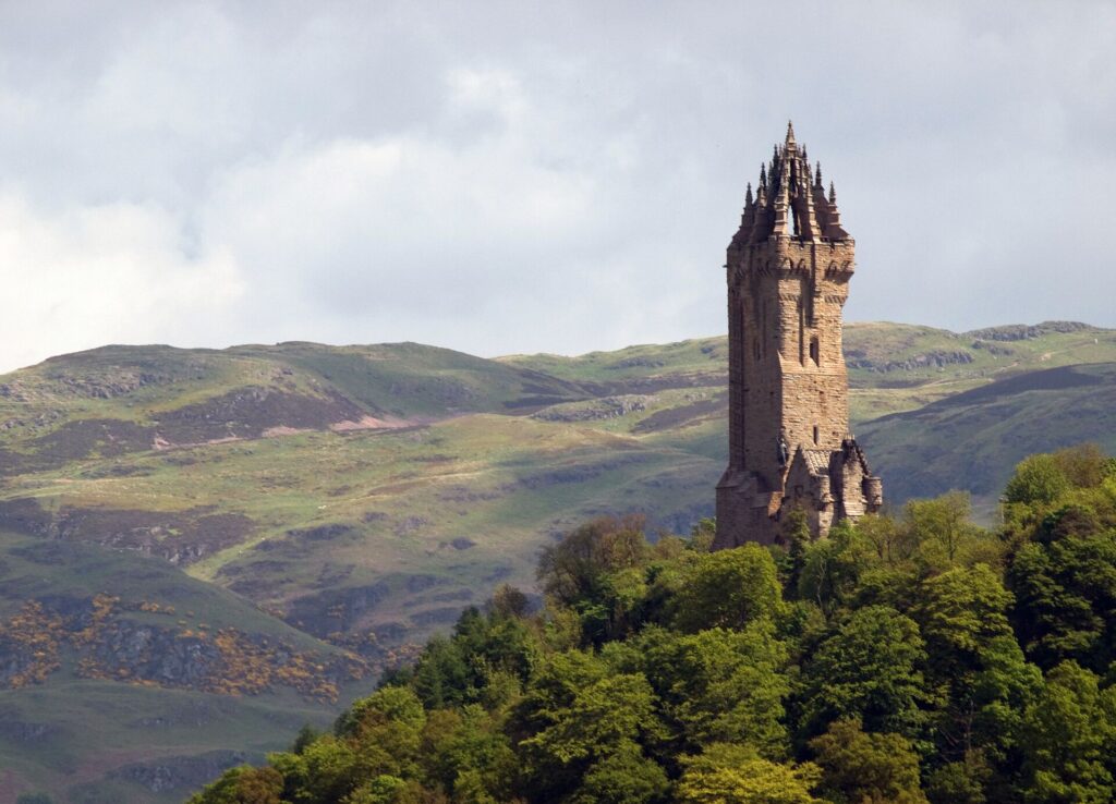 An ancient stone tower sits among the green hills of Stirling, Scotland