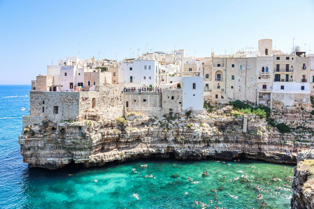 White stone houses sit high on a rock in Puglia, Italy.