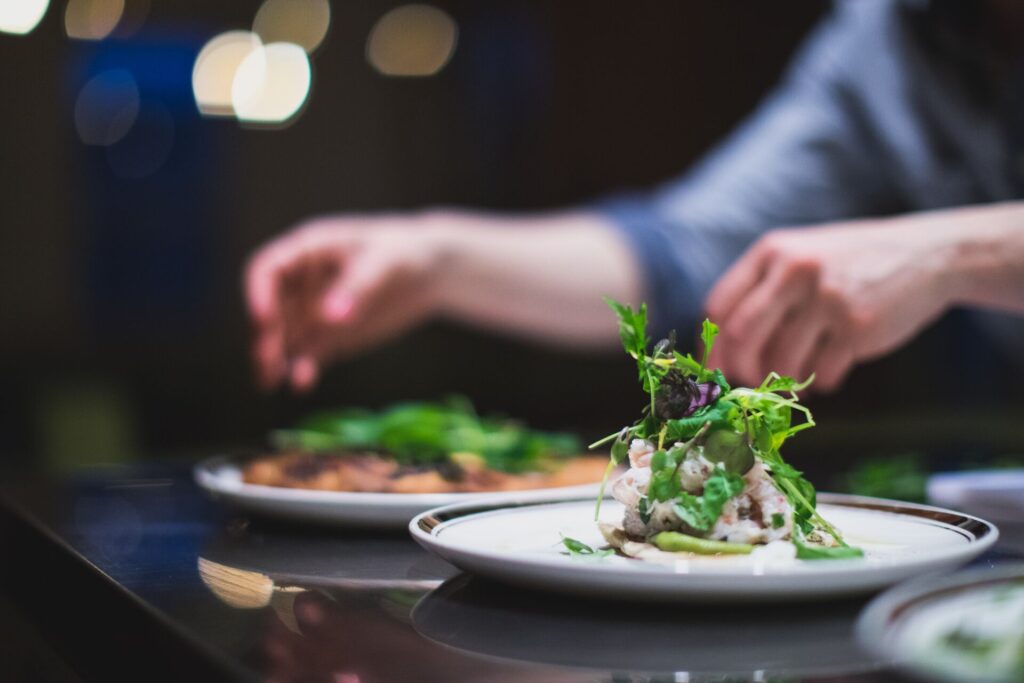 Hands carefully garnish high end food dishes