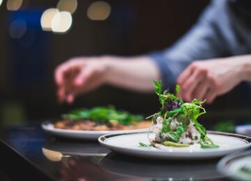 Hands carefully garnish high end food dishes
