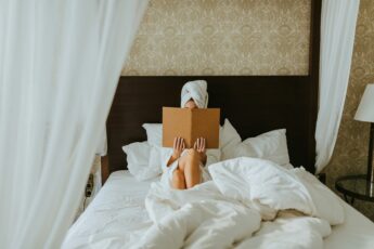 A woman reads while sat in a large hotel bed