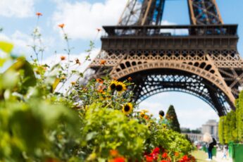 The base of Paris' Eiffel Tower, with bright flowers and leaves in the picture.