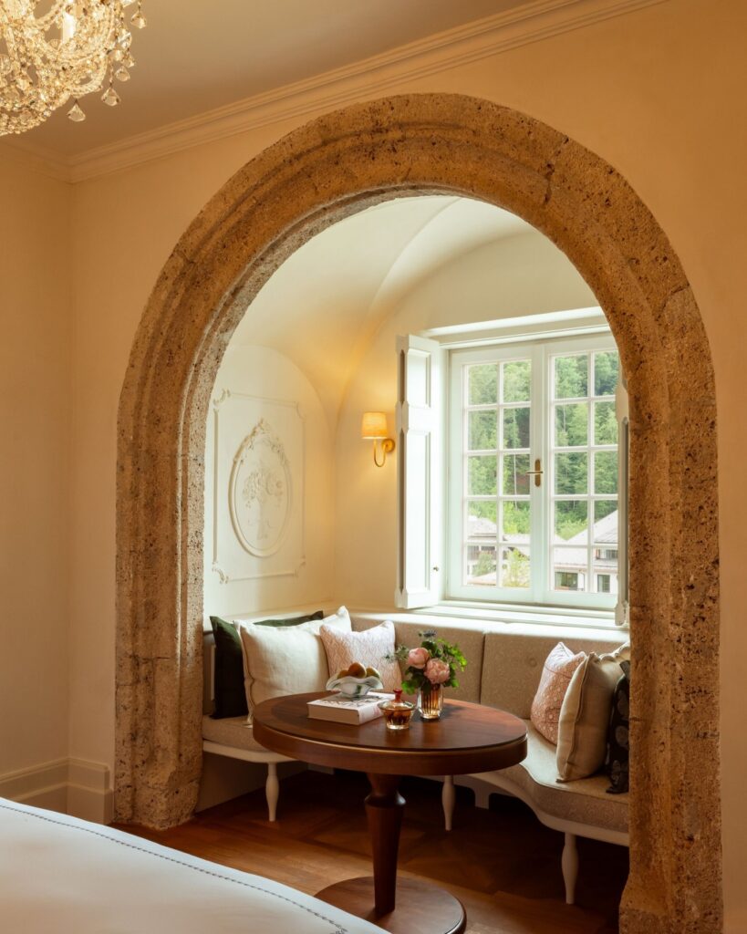 Interior of bedroom, with window bench seat within looking out onto a garden 