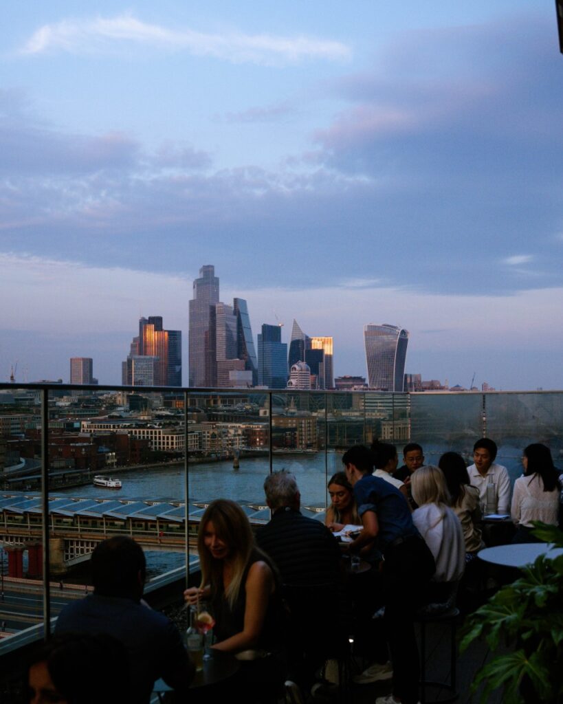 People on a rooftop terrace overlooking the City of London and the River Thames