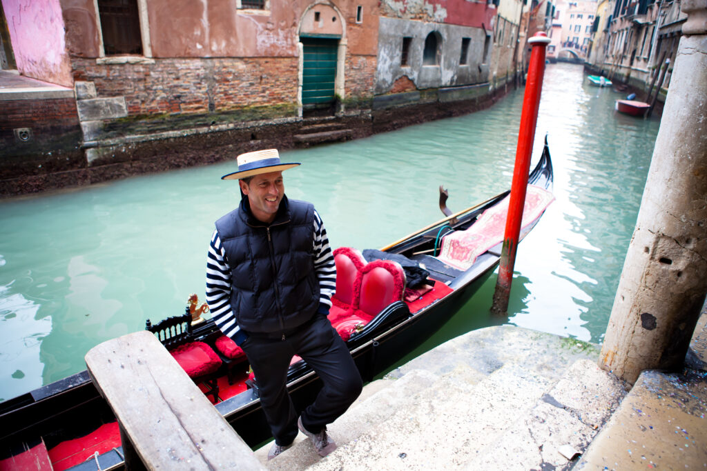 A Gondolier welcoming tourists on a canal in Venice, Italy.