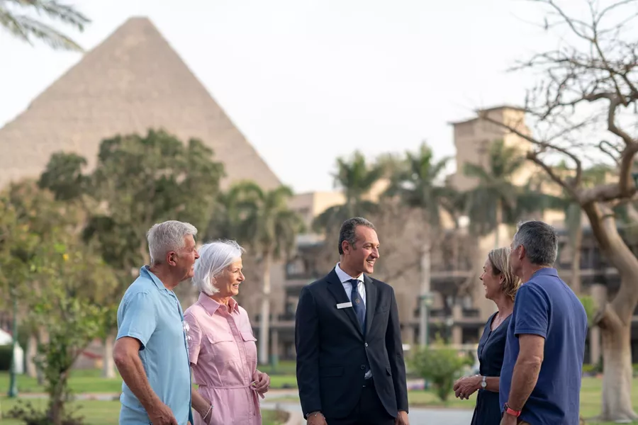 Two couples of different ages smilingly chat with a man in a suit