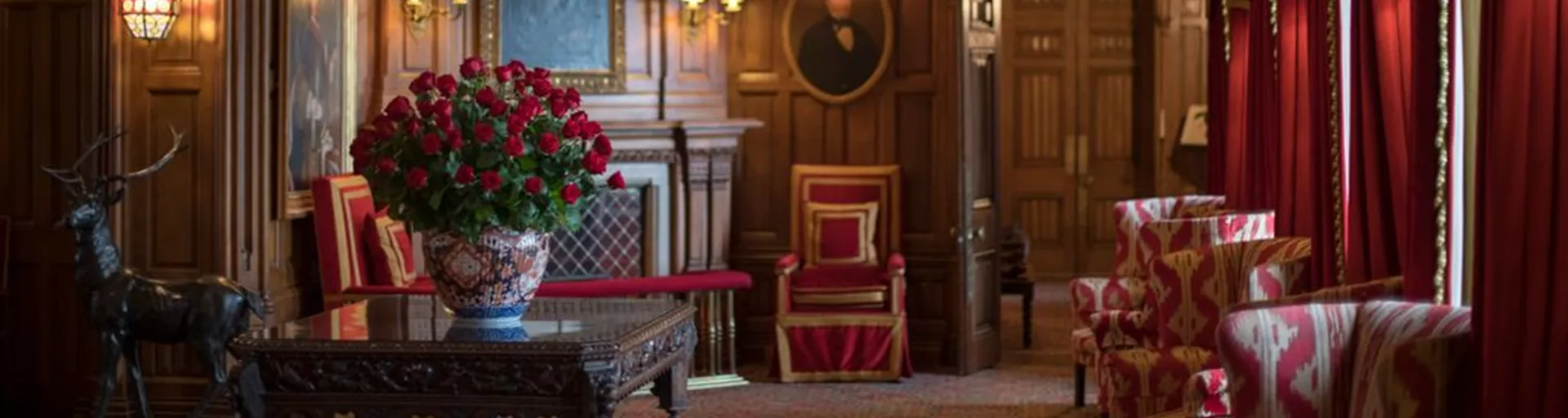 A view of a grand room in a castle with a chandelier and a large vase with roses