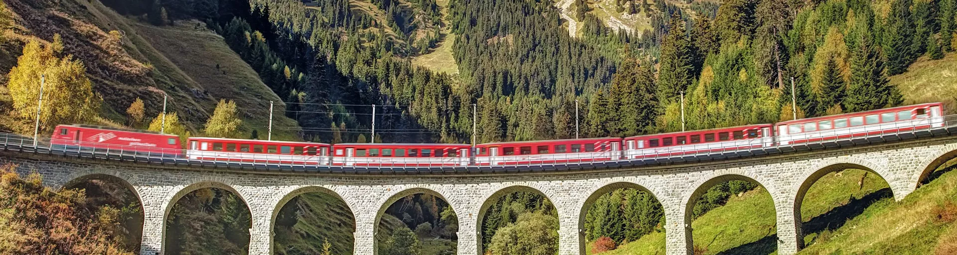 Red train on a viaduct in the Swiss Alps on a sunny day